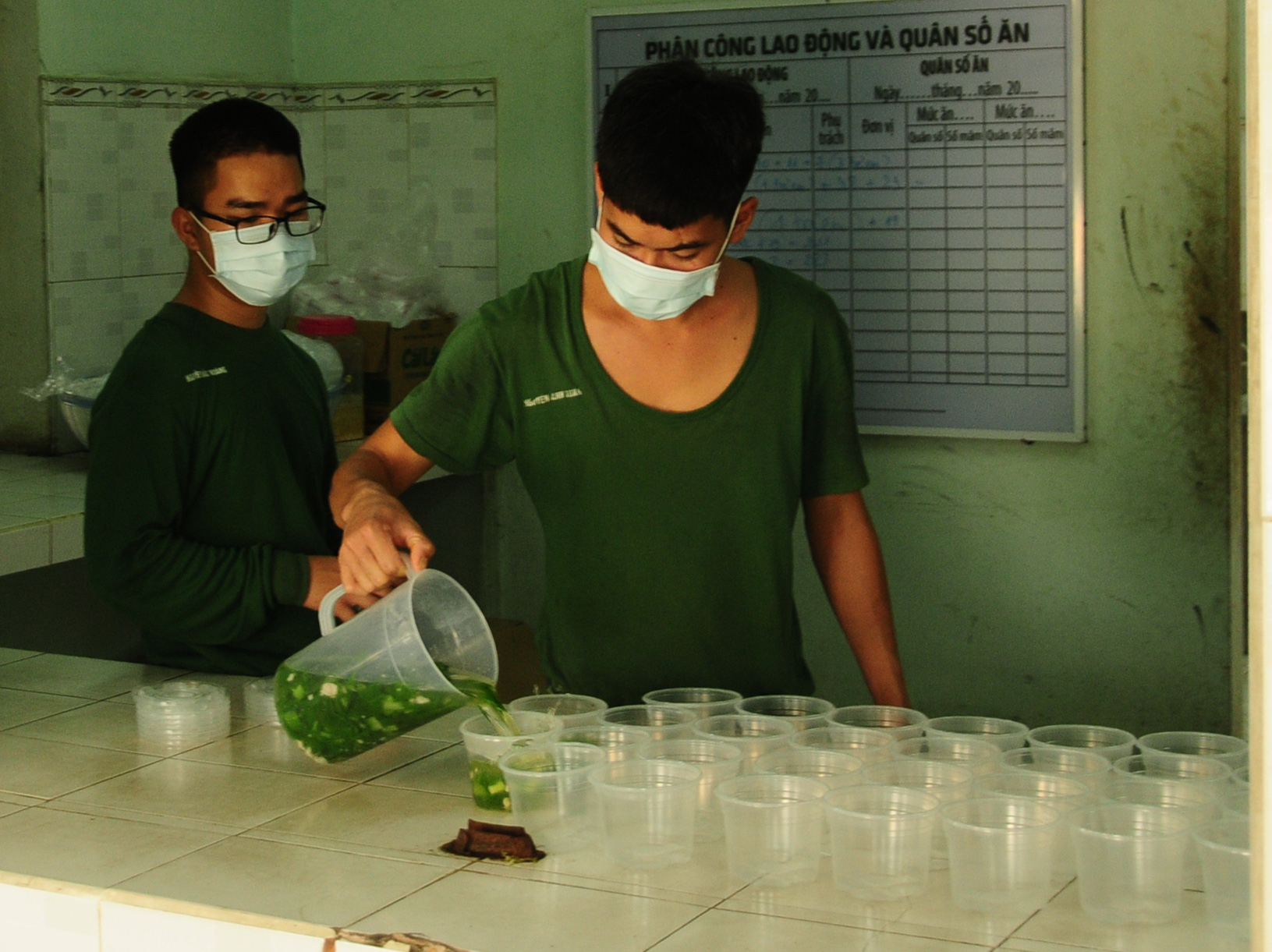 Two soldiers distribute food into portions for quarantined people at Hanoi Capital High Command’s Military School in Hanoi, Vietnam. Photo: Nguyen Khanh / Tuoi Tre
