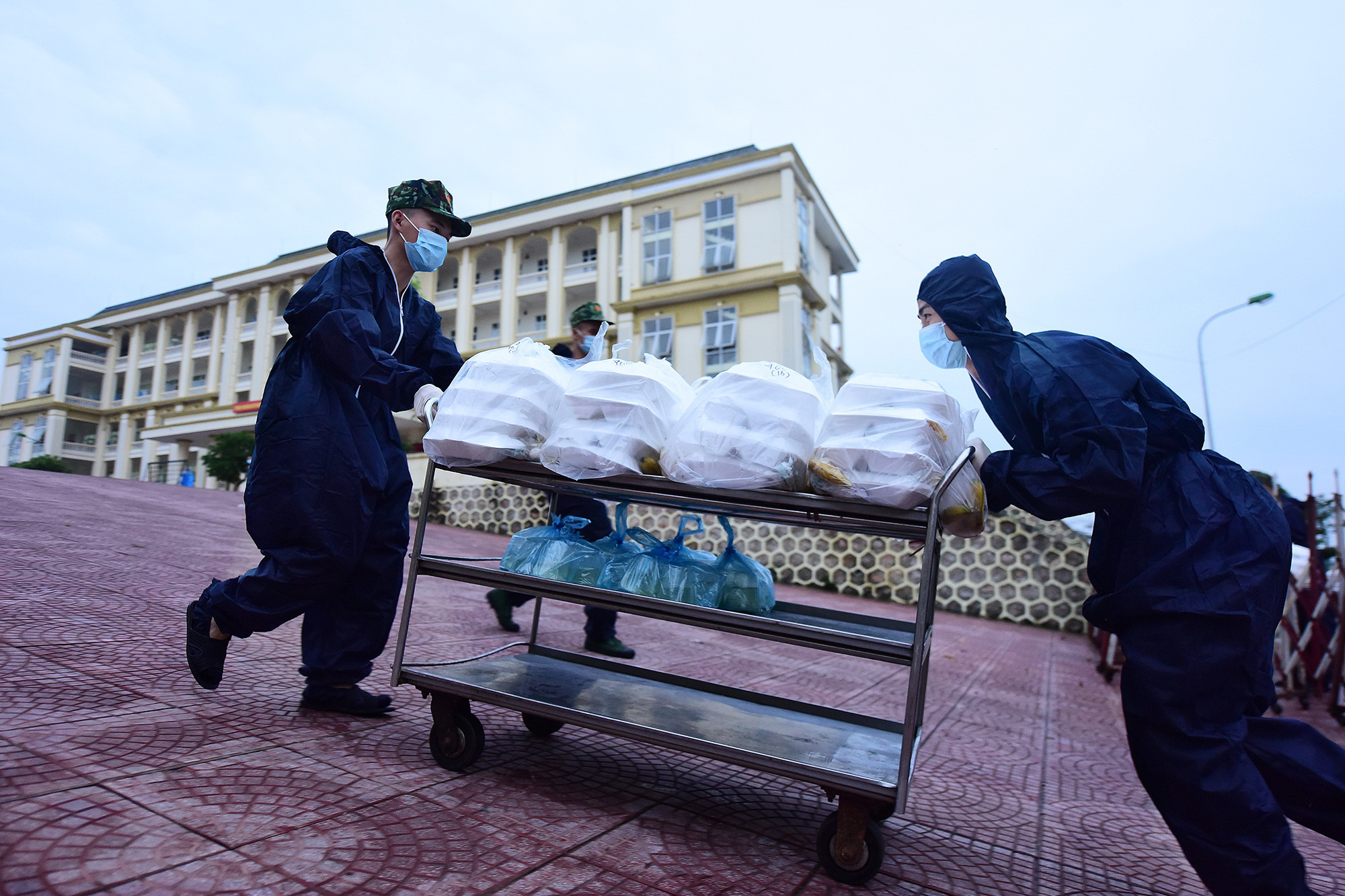 Two soldiers are pushing a trolley topped with boxes of rice on their way to the quarantined zone in Vietnam. Photo: Nguyen Khanh / Tuoi Tre