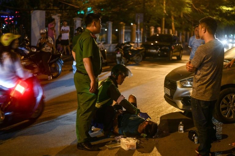 An unofficial emergency responder and a police officer are seen at the scene of a traffic accident in Hanoi. Photo: AFP