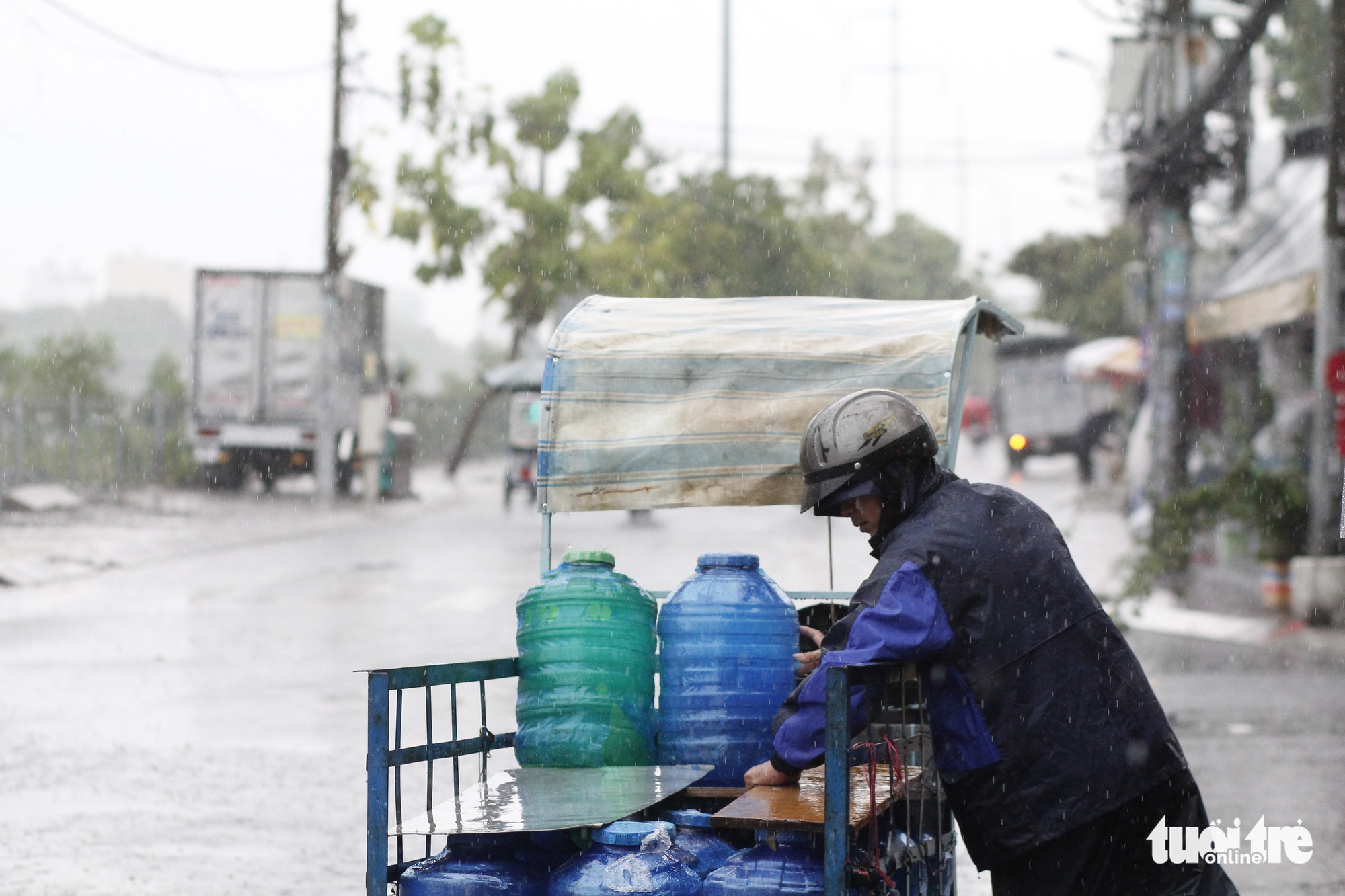 A man delivers water bottles under the rain in District 7, Ho Chi Minh City, May 30, 2020. Photo: Chau Tuan / Tuoi Tre