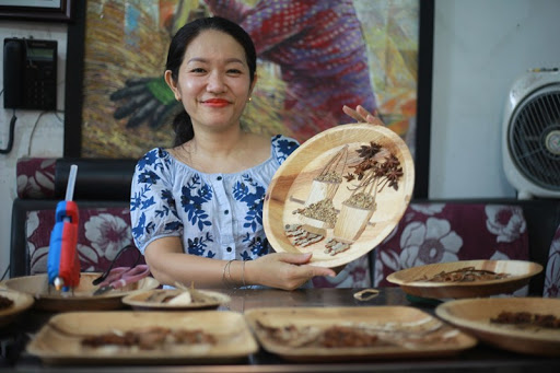 Artist Nguyen Thi Dieu Hien and an artwork made from areca leaves are seen in this photo on Facebook.