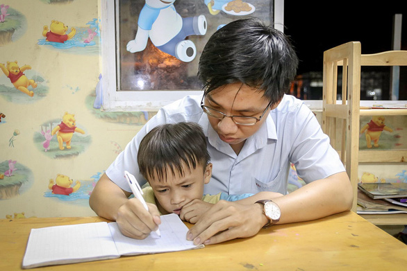 Danh Tuan Anh teaches one of his young students how to write in his tuition-free classes held in District 7, Ho Chi Minh City, Vietnam. Photo: Dieu Qui / Tuoi Tre