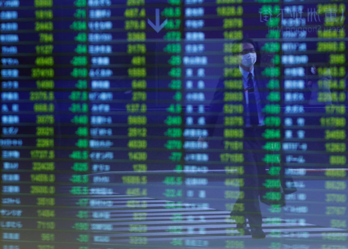 A man wearing protective face mask, following an outbreak of the coronavirus, is reflected on a screen displaying stock prices outside a brokerage in Tokyo, Japan March 6, 2020. Photo: Reuters