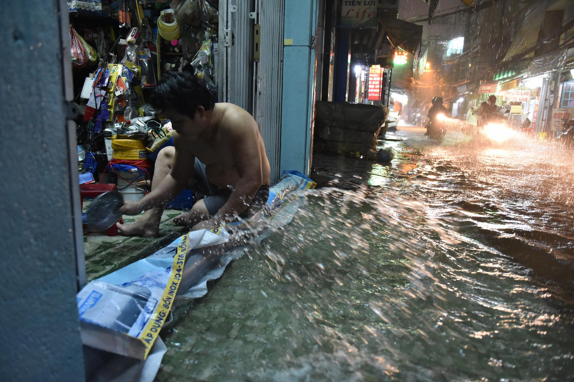 A man scoops rainwater from his house in Ho Chi Minh City, August 6, 2020. Photo: Ngoc Phuong / Tuoi Tre