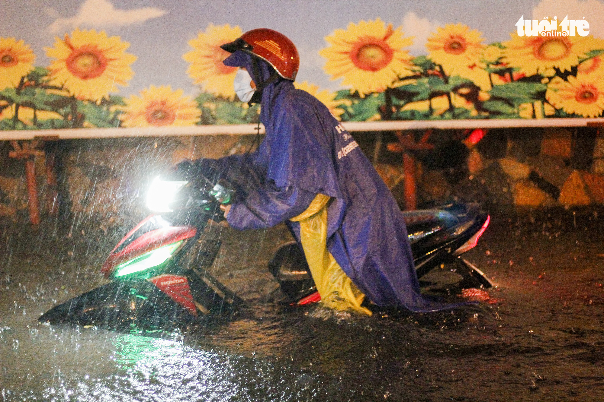 A resident pushes a motorcycle in knee-deep water, Ho Chi Minh City, August 6, 2020. Photo: Chau Tuan / Tuoi Tre