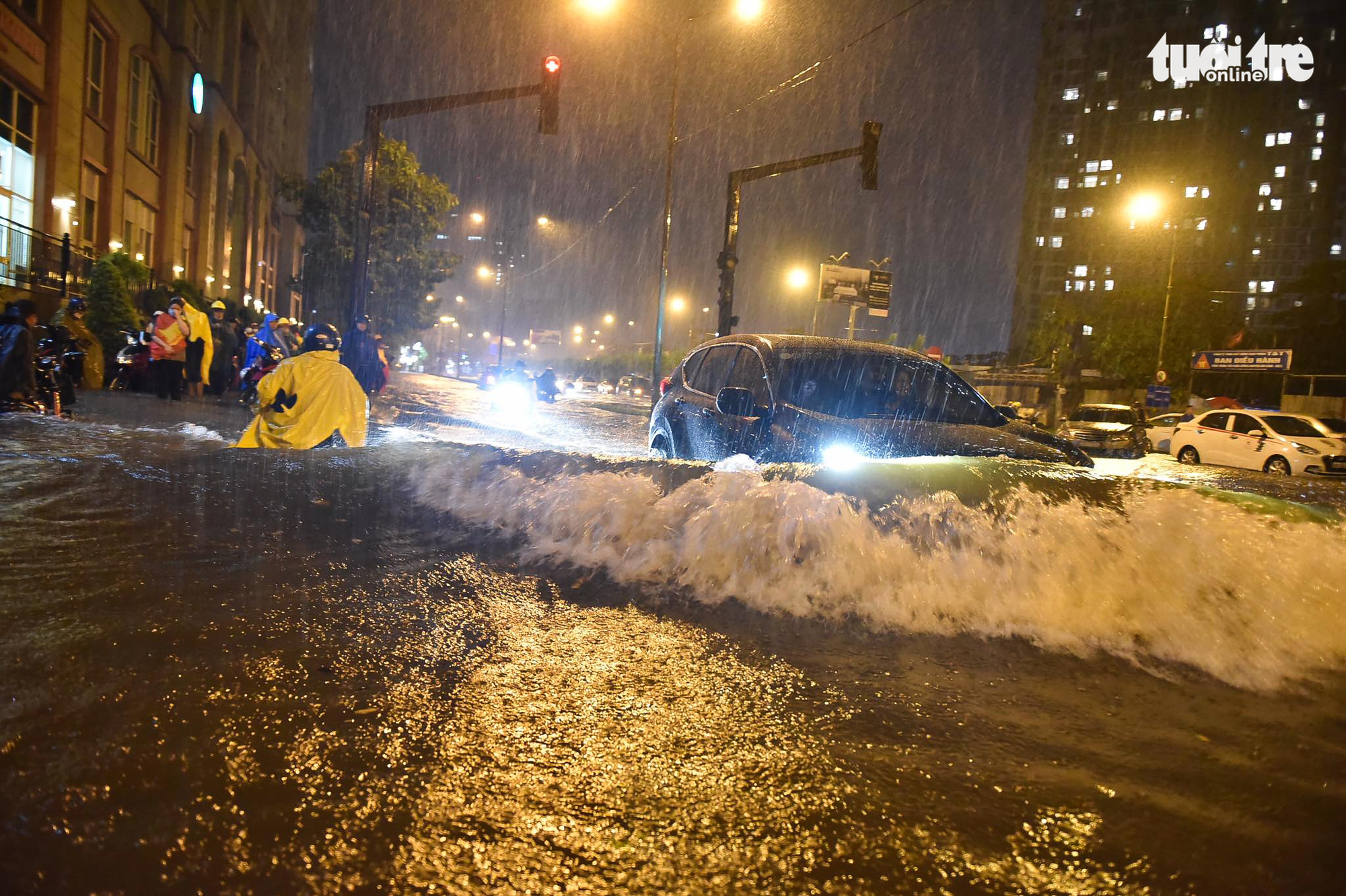 Waves of floodwater spill over as a car travels on an inundated street in Ho Chi Minh City, August 6, 2020. Photo: Ngoc Phuong / Tuoi Tre