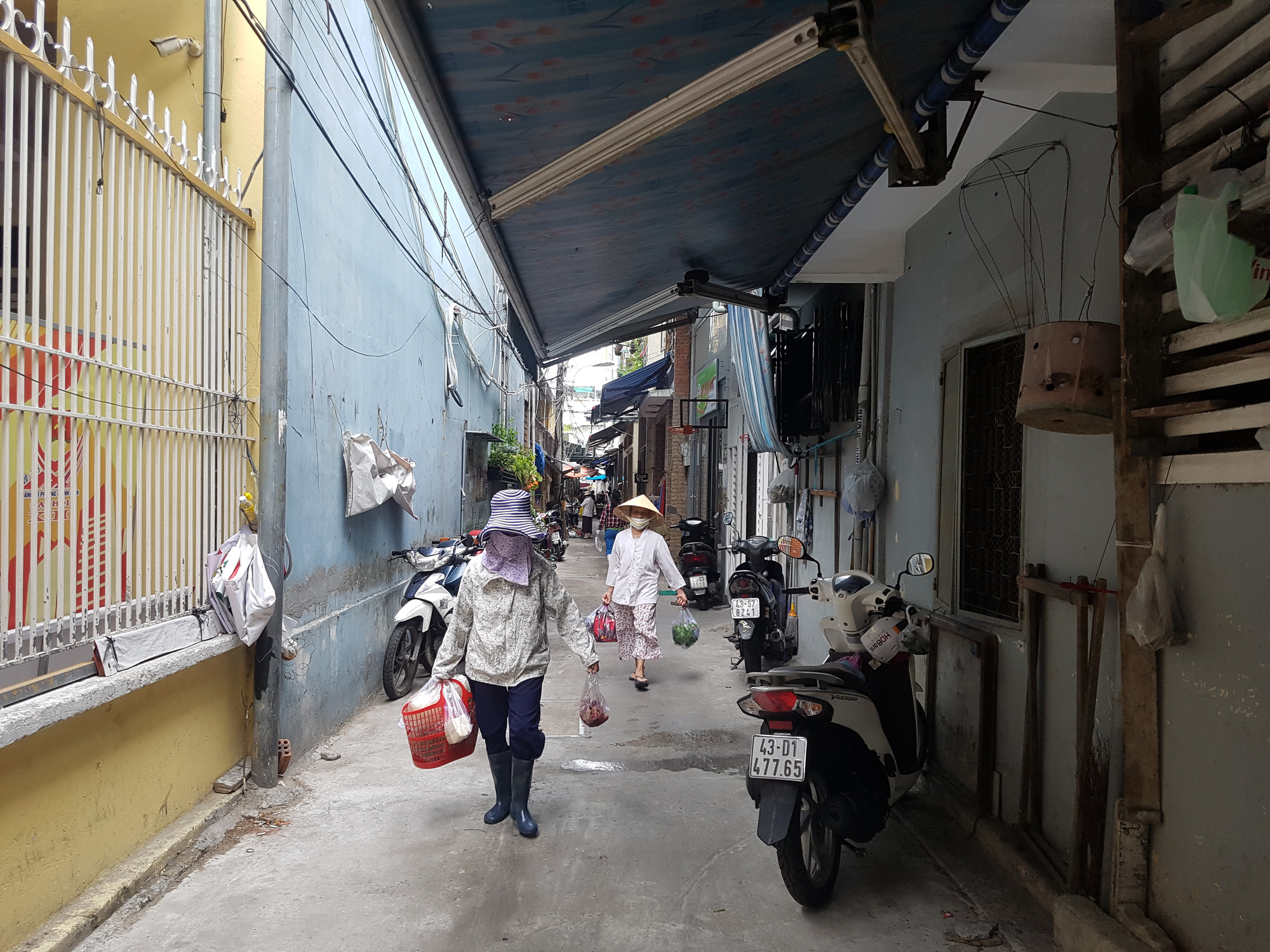 Residents carry grocery as they exit a market in Da Nang City, Vietnam, August 12, 2020. Photo: Huu Kha / Tuoi Tre