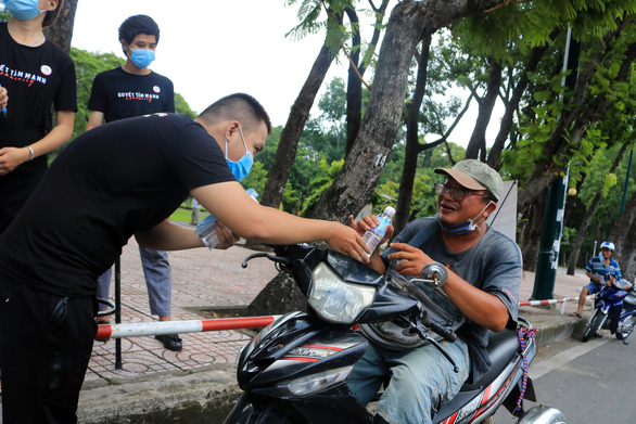 A member of the group ‘Quyet tam manh’ gives a bottle of water to a lottery ticket seller in Go Vap District, Ho Chi Minh City, September 2, 2020. Photo: Nhat Thinh / Tuoi Tre