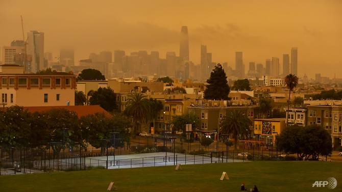 People relax under an orange smoke-filled sky at Dolores Park in San Francisco, California on Sep 9, 2020. Photo: