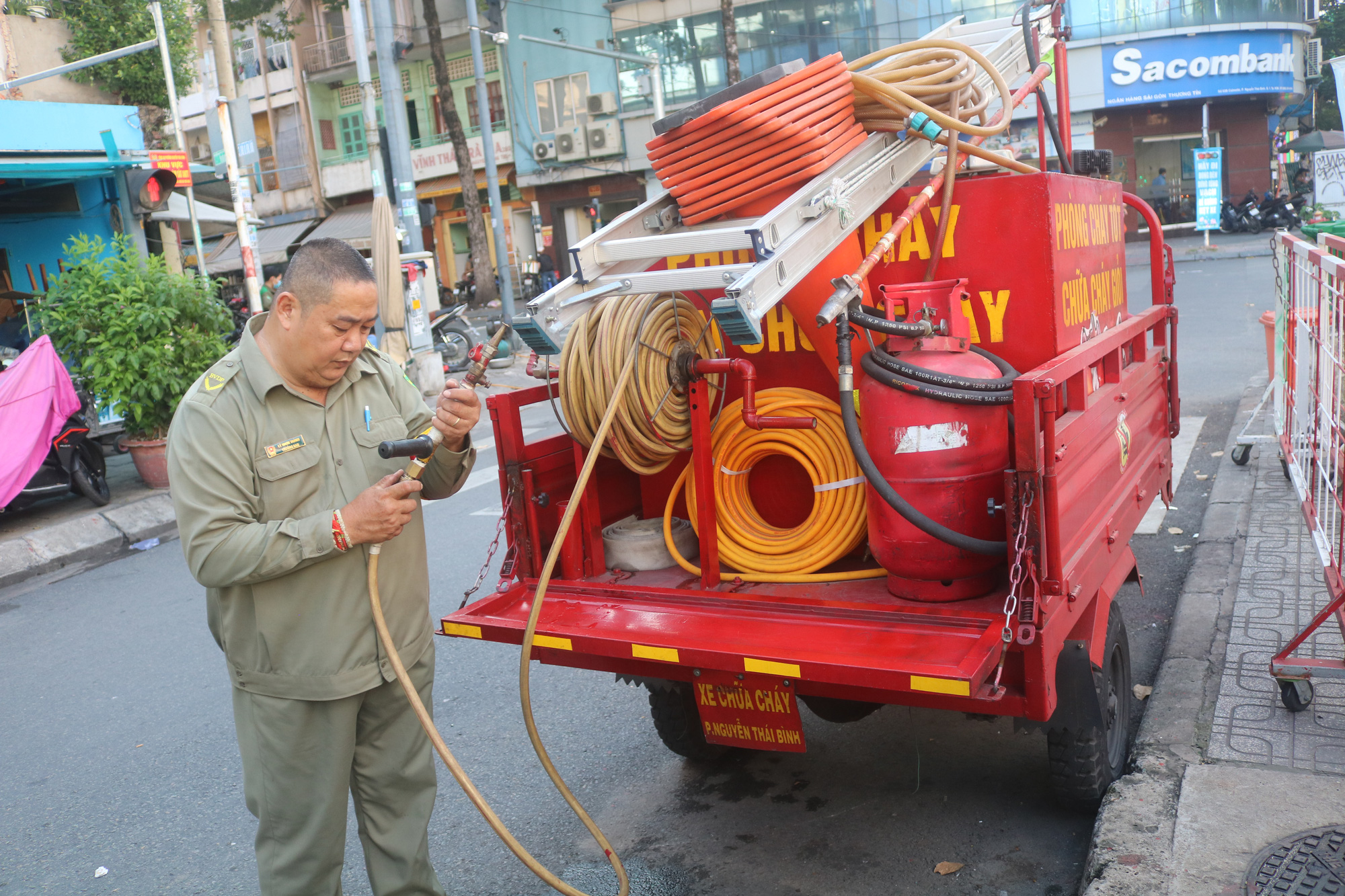 Ly Nhon Thanh inspects the hose of his fire bike modified from a three-wheeled motorbike. Photo: Kim Ut / Tuoi Tre