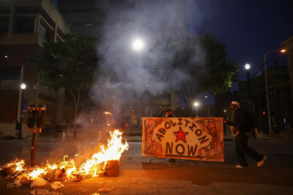 rotesters carry a sign as they walk by a fire in front of the Louis D. Brandeis Hall of Justice after a grand jury voted to indict one of three white police officers for wanton endangerment in the death of Breonna Taylor, who was shot dead by police in her apartment, in Louisville, Kentucky, U.S. September 23, 2020. Photo: Reuters