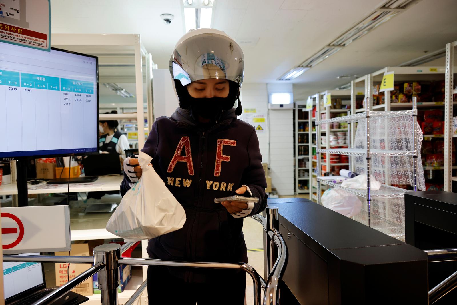Chey Young-ah, a dispatch rider, checks her mobile phone while delivering groceries in Seongnam, South Korea, October 7, 2020. Photo: Reuters