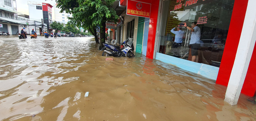 People are trapped by rising water inside a store on a street in Can Tho City, Vietnam, October 19, 2020. Photo: Chi Quoc / Tuoi Tre