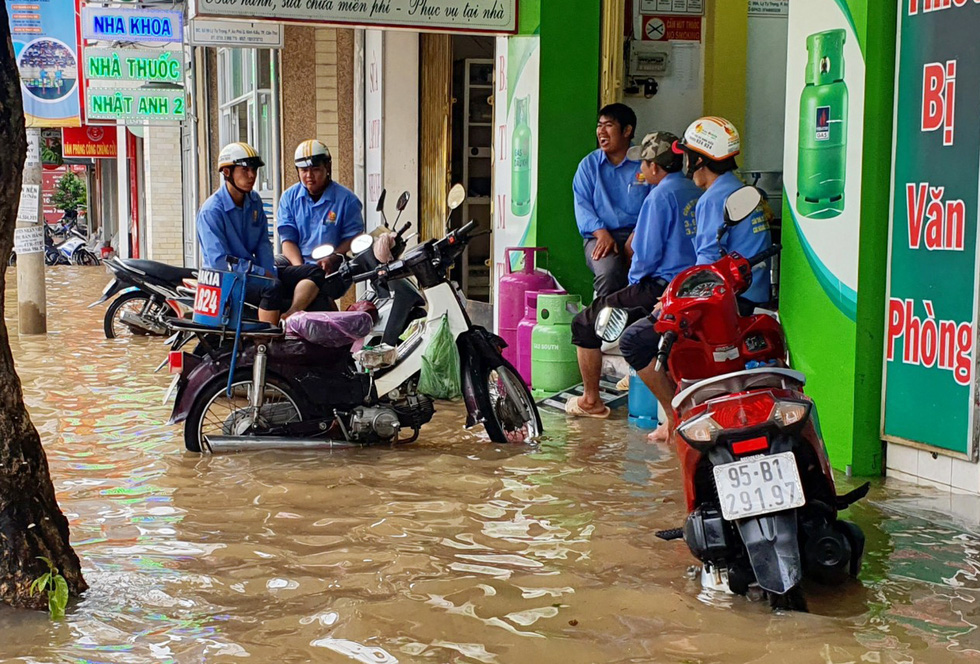Deliverymen are trapped by rising water in front of a store on a street in Can Tho City, Vietnam, October 19, 2020. Photo: Chi Quoc / Tuoi Tre