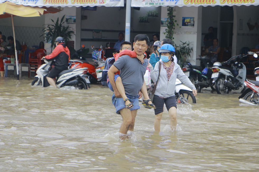 A man carries his son piggy-back to school in Can Tho City, Vietnam, October 19, 2020. Photo: Chi Quoc / Tuoi Tre