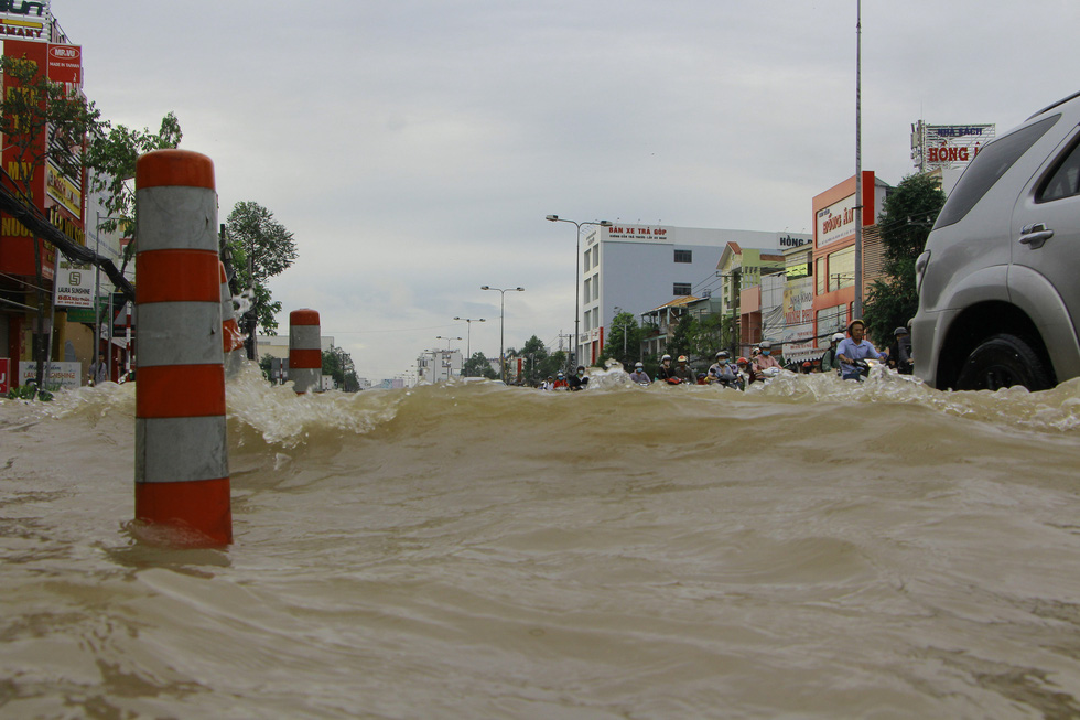Rising water makes waves lash nearby vehicles on a street in Can Tho City, Vietnam, October 19, 2020. Photo: Chi Cong / Tuoi Tre
