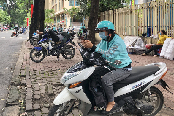 Tran Thi Thu Ngan, 21, is spotted waiting opposite a bubble milk tea shop in Ho Chi Minh City, Vietnam for new orders on her phone. Photo: Dieu Qui/ Tuoi Tre