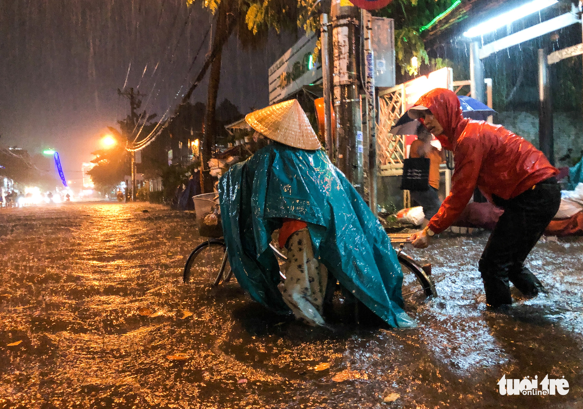 A man helps a cyclist on an inundated road in Ho Chi Minh City, October 31, 2020. Photo: Chau Tuan / Tuoi Tre