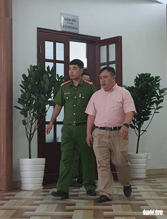 Nguyen Minh Khai, director of the Ho Chi Minh City Eye Hospital, leaves with a police officer following a working session on November 4, 2020. Photo: Huong Thao / Tuoi Tre