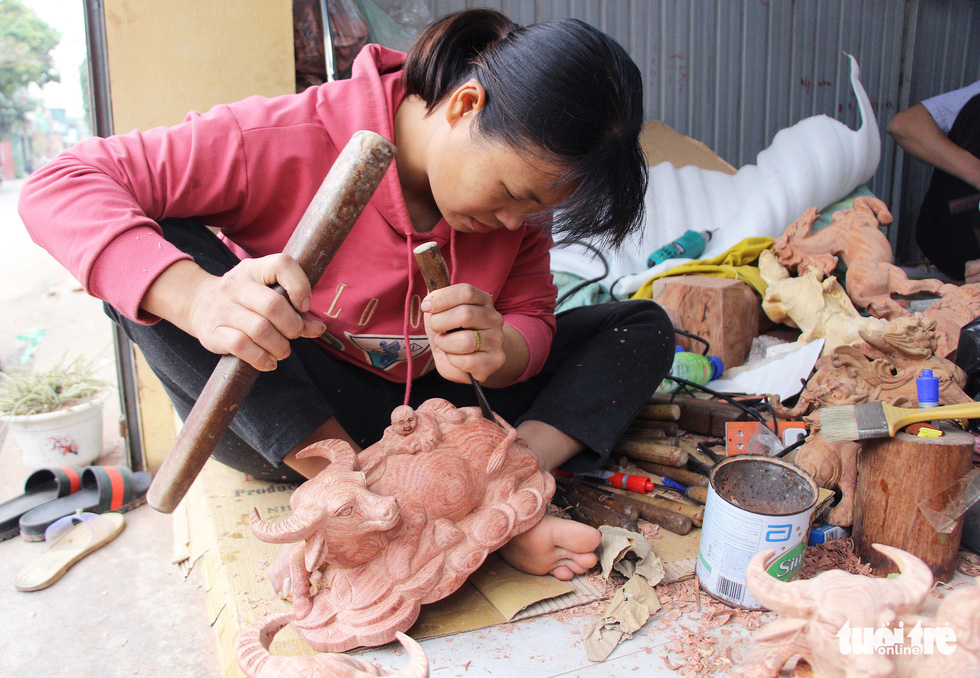Tran Thi Thuong carves a wooden buffalo at Dinh Quan Village, Tien Phong Commune of Thuong Tin District, Hanoi. Photo: Ha Quan / Tuoi Tre