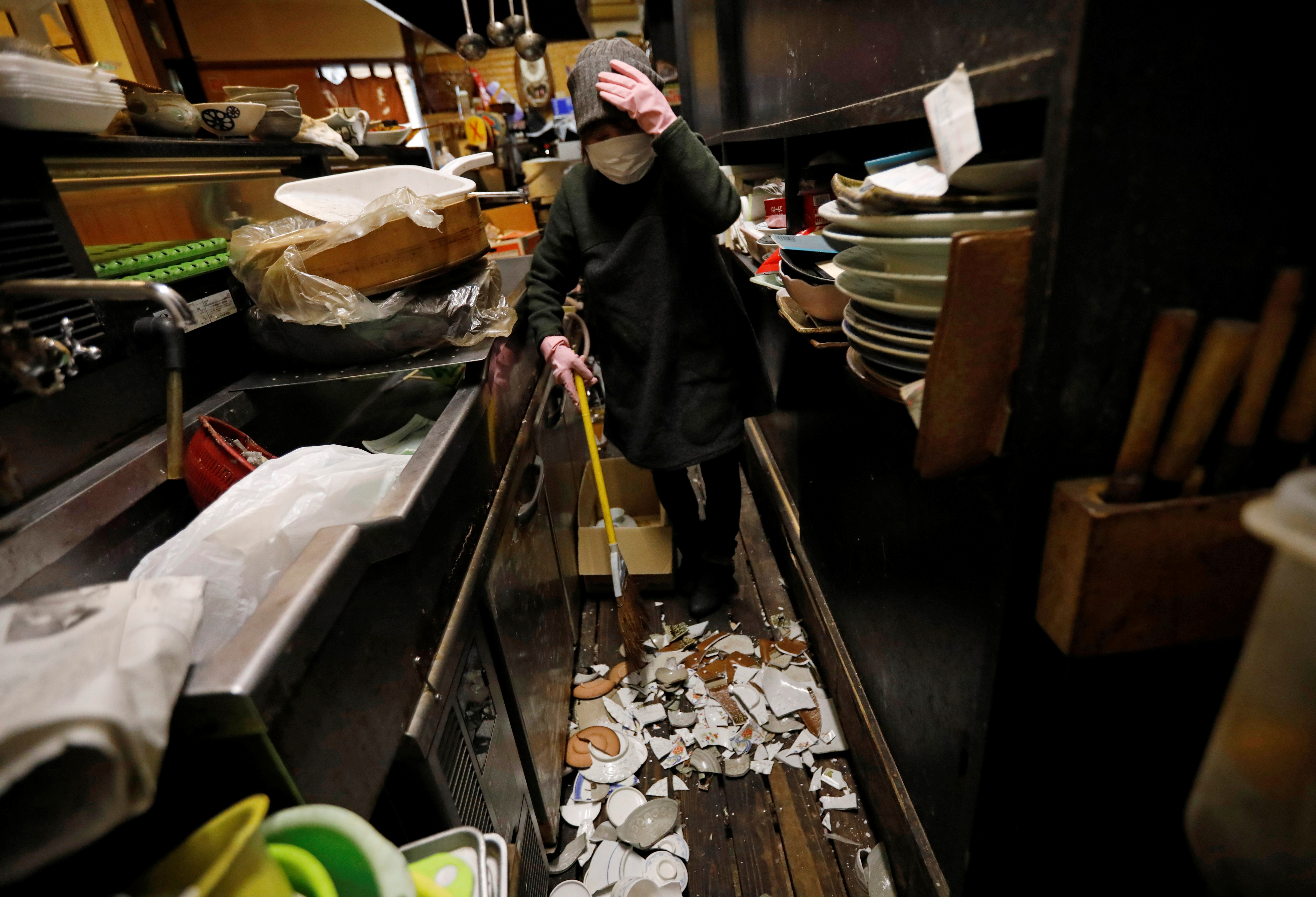 Mitsue Hisa, 70, an owner of a Japanese izakaya pub, cleans up broken dishes at her shop after a strong quake in Iwaki, Fukushima prefecture Japan, February 14, 2021. Photo: Reuters