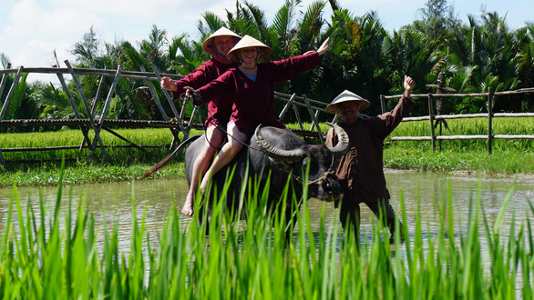 Two foreign tourists are excited with their first buffalo ride. Photo: B.D / Tuoi Tre