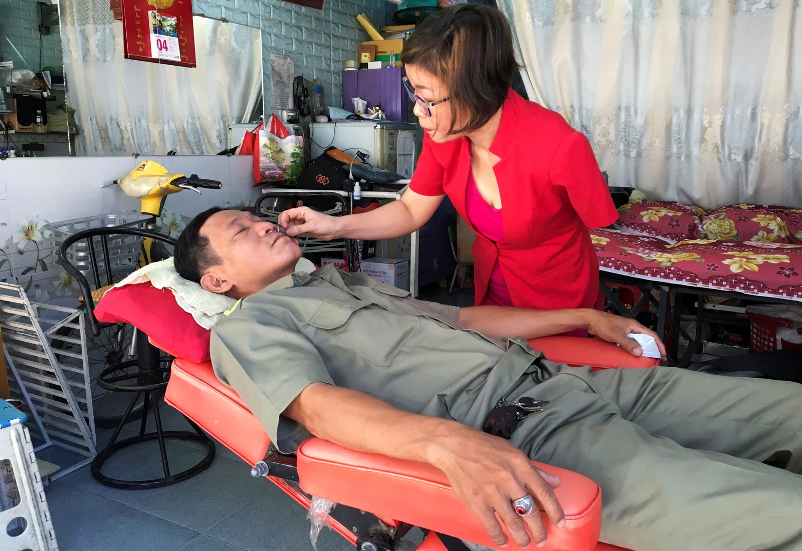 Le Thi Kim Tram, who lost her left arm in a traffic accident four years ago, works at her barbershop in Ho Chi Minh City, Vietnam March 5, 2021. Photo: Reuters