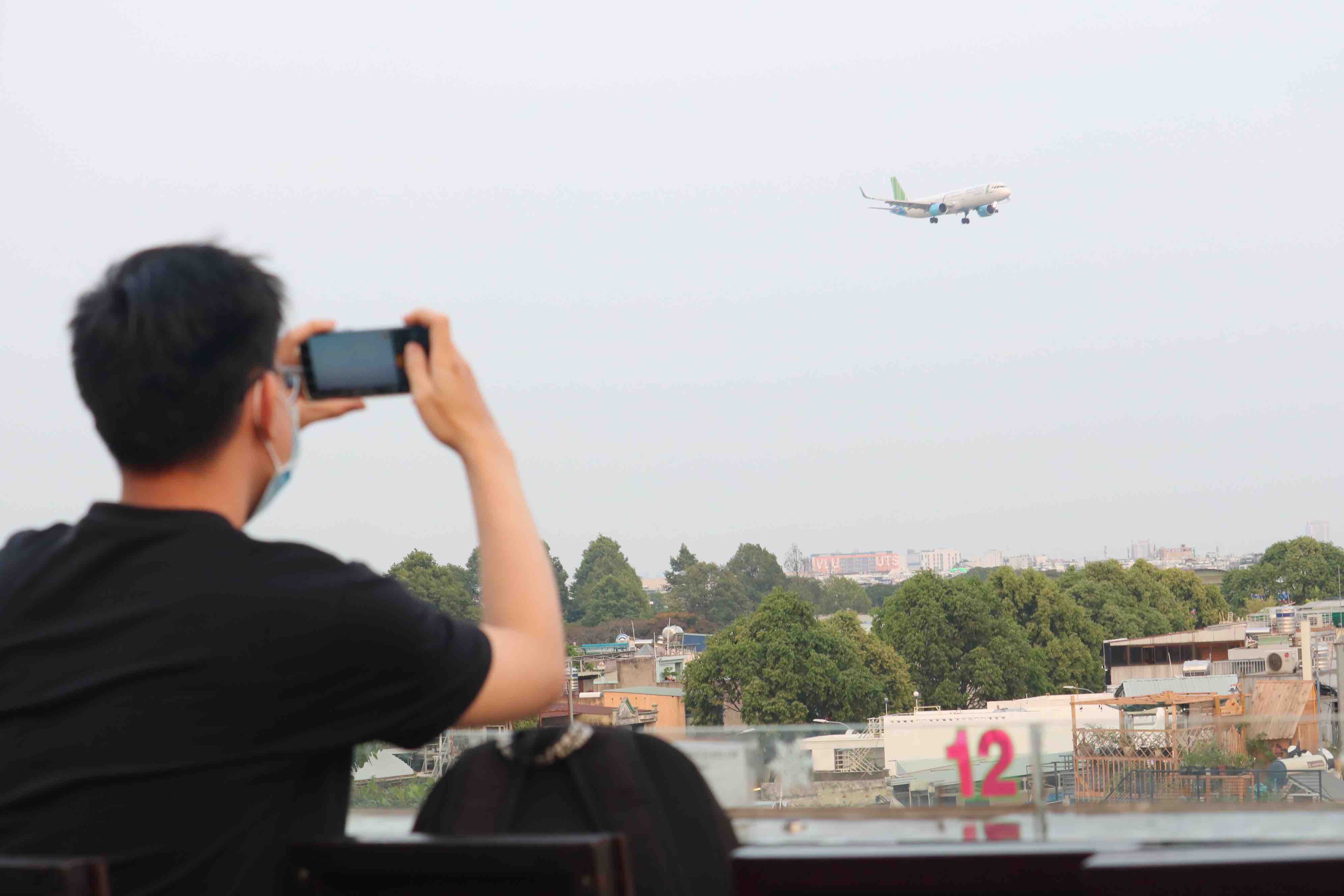 A customer photographs an airplane as it passes by at Ngam May Bay café in Go Vap District, Ho Chi Minh City. Photo: Hoang An / Tuoi Tre