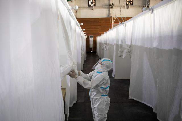 A health worker in personal protective equipment draws the curtains of a makeshift room used by a coronavirus disease (COVID-19) patient in a quarantine facility in Manila, Philippines, April 15, 2021. Photo: Reuters