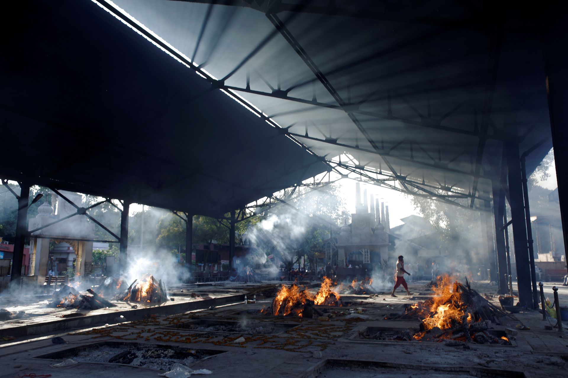 A person walks past funeral fires of those who died from the coronavirus disease (COVID-19) at a crematorium in New Delhi, India April 24, 2021. Photo: Reuters