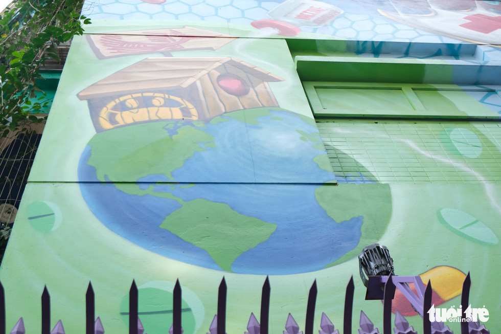 A Vietnamese house sits on the earth in a mural on the wall of a house at the Van Phu residential quarter in Ha Dong District, Hanoi. The painter says this artwork promotes Vietnamese unity in the fight against COVID-19. Photo: Ha Thanh