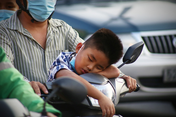 This image shows a boy dozing on the handlebars of a motorbike on the way back to Ho Chi Minh City on May 2, 2021. Photo: Nhat Thinh / Tuoi Tre