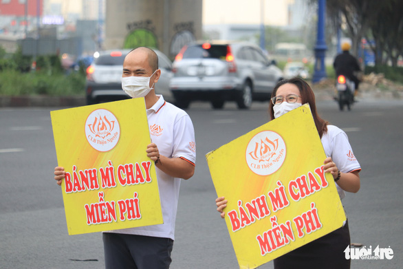 Mai Anh and Anh Tuan dance with a sign to catch the passersby. Photo: Hoang An / Tuoi Tre