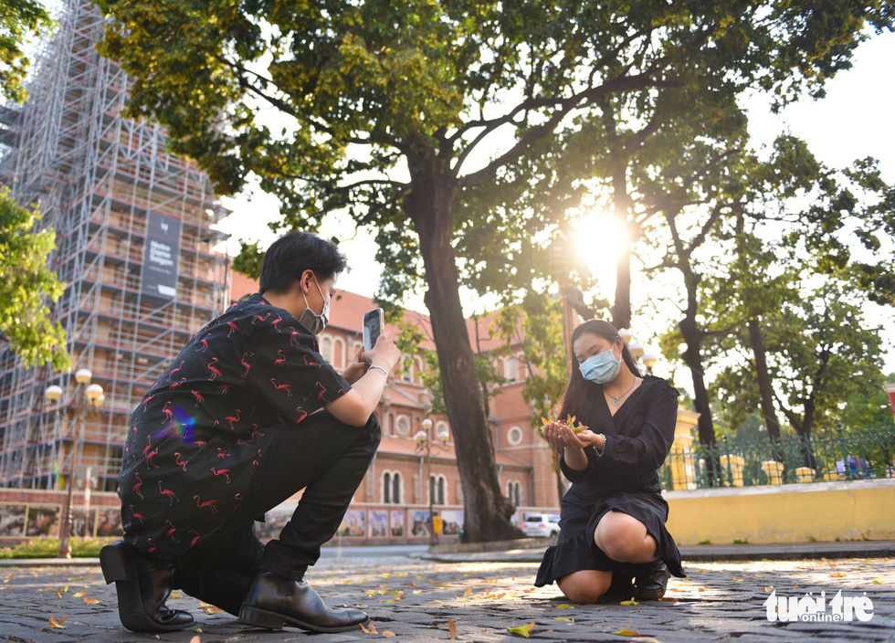 A man takes a picture of a woman with cho nau seeds near the Notre-Dame Cathedral Basilica of Saigon in District 1. Photo: Ngoc Phuong / Tuoi Tre