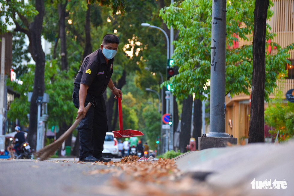 Nguyen Van Hoang, a security guard at a restaurant on Le Quy Don Street in District 3, sweeps cho nau seeds from the street. Photo: