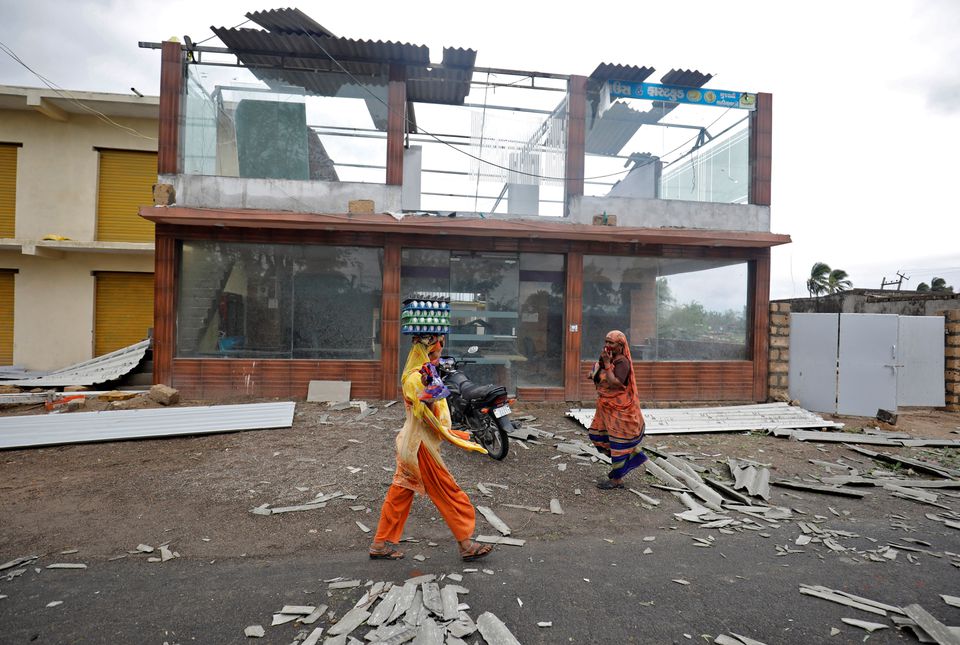 A woman carrying eggs walks past a damaged commercial building after Cyclone Tauktae hit, in Kodinar, in the western state of Gujarat, India, May 18, 2021. Photo: Reuters