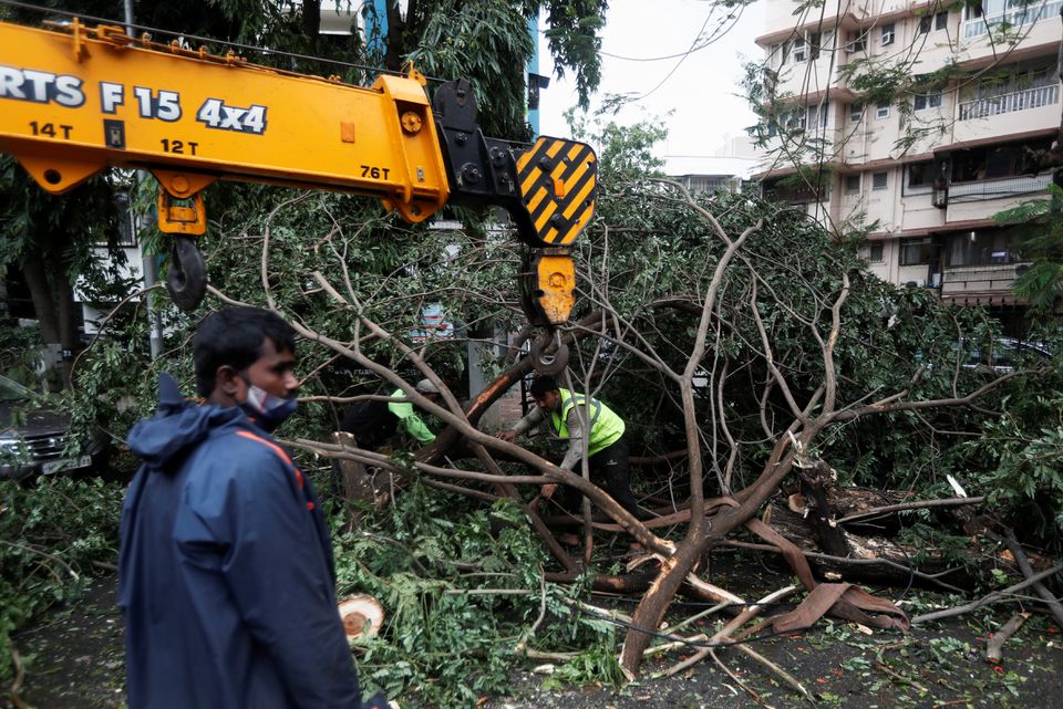 People attempt to remove uprooted trees from the entrance of a residential building after strong winds caused by Cyclone Tauktae, in Mumbai, India, May 18, 2021.Photo: Reuters