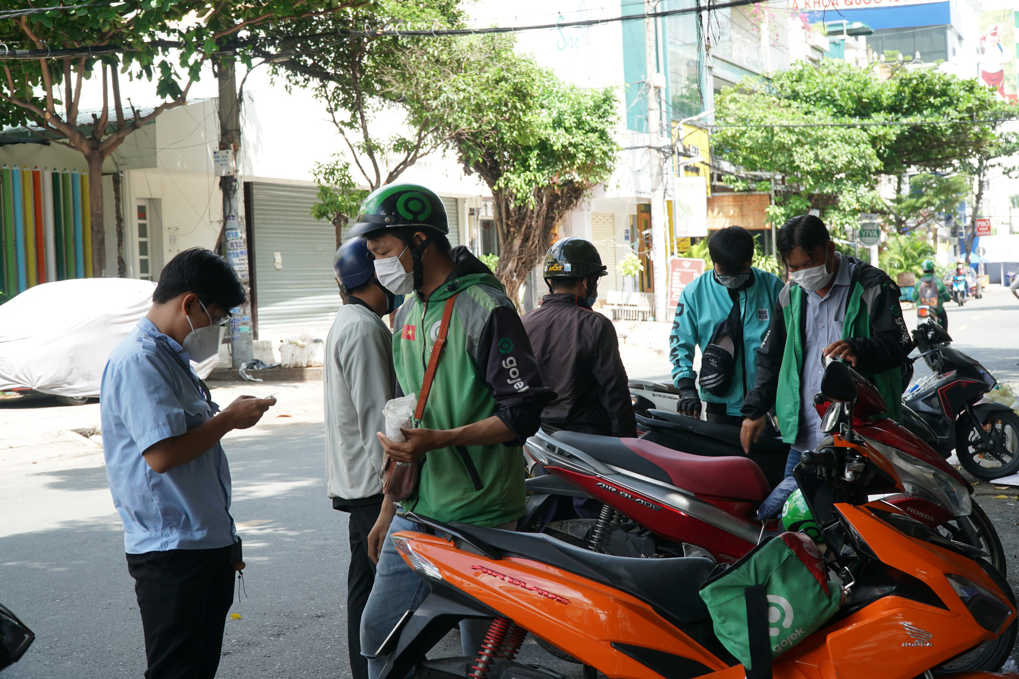 Delivery workers are booked for violating limit on public gatherings in Binh Thanh District, Ho Chi Minh City, June 24, 2021. Photo: Dan Thuan / Tuoi Tre