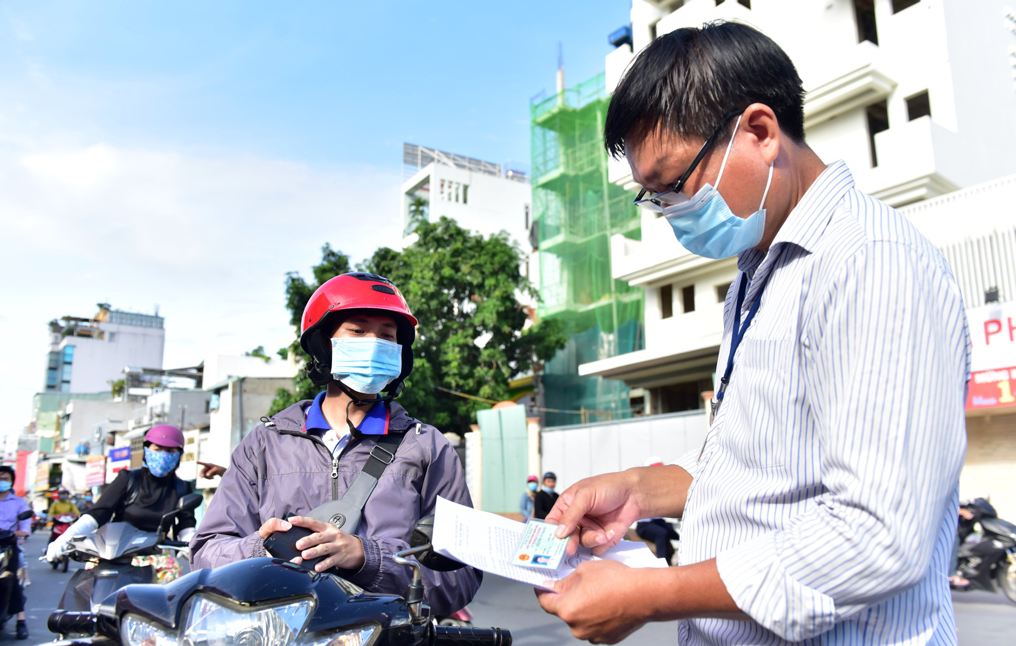 An officer checks personal documents belonging to a commuter on a street in Phu Nhuan District, Ho Chi Minh City, July 9, 2021. Photo: Duyen Phan / Tuoi Tre
