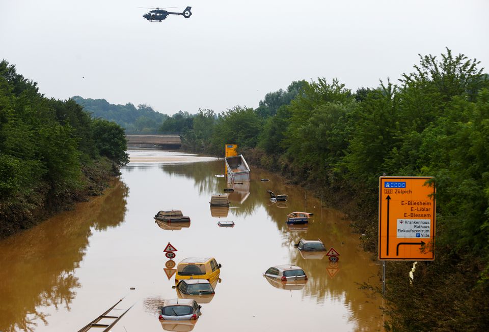 A helicopter flies above cars partially submerged in floodwaters on the road following heavy rainfalls in Erftstadt-Blessem, Germany, July 17, 2021. Photo: Reuters