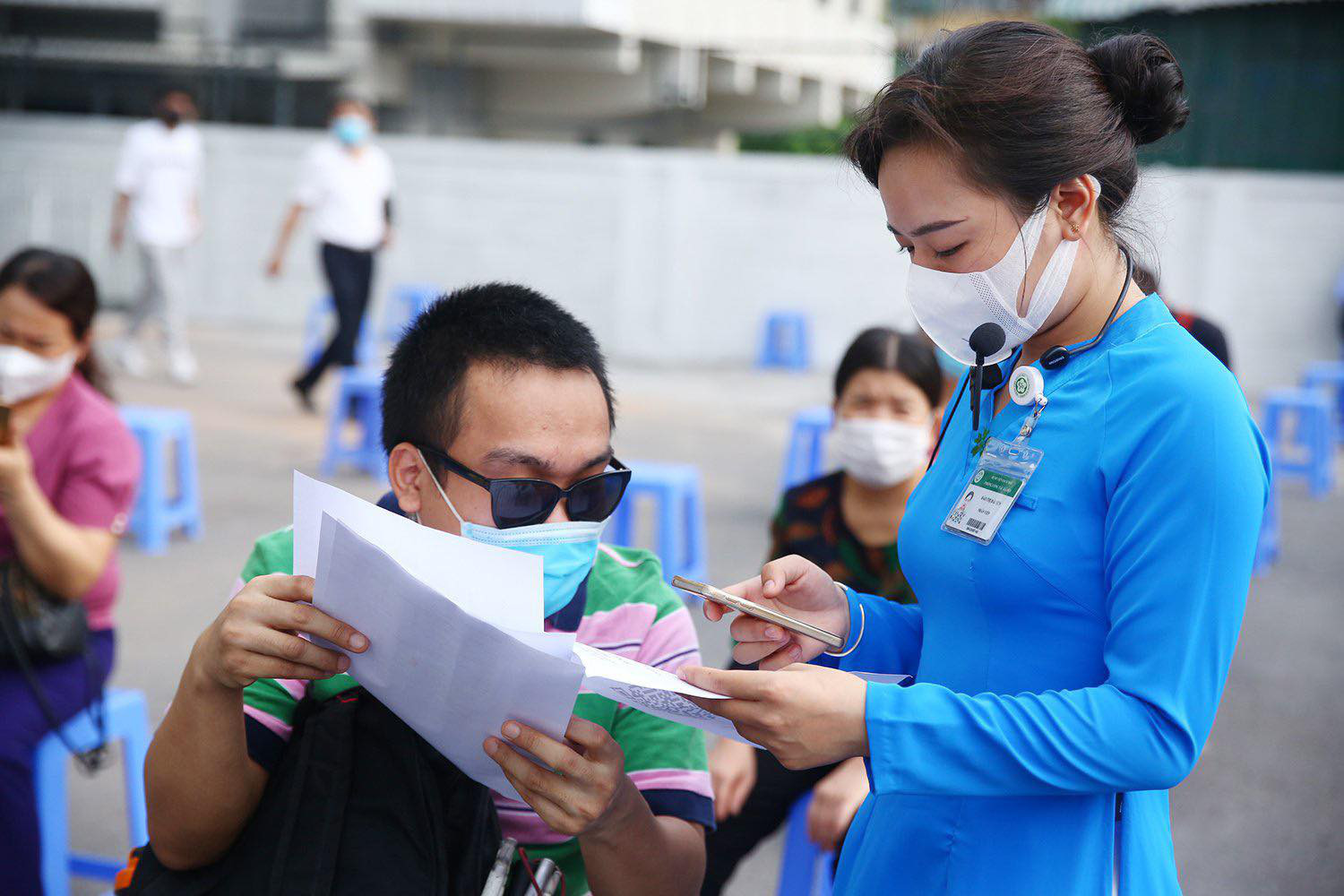 A staff member assists a disabled worker with paperwork before a COVID-19 vaccination session in Hanoi, July 29, 2021. Photo: Ministry of Planning and Investment