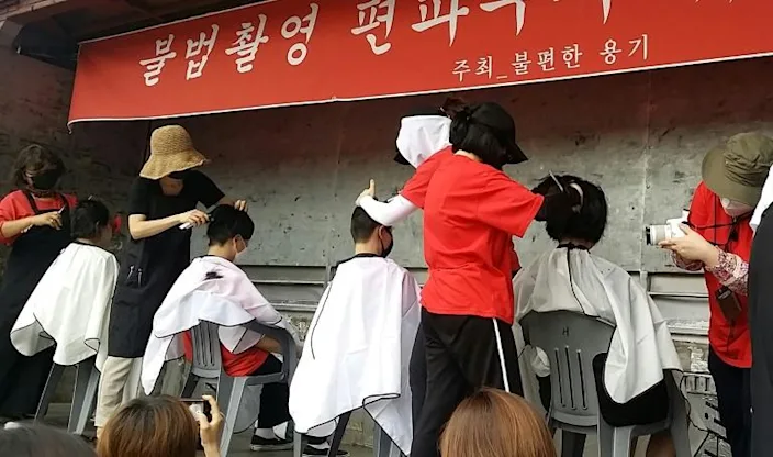 Women shave their heads at a protest against spycam crime. Photo: AFP