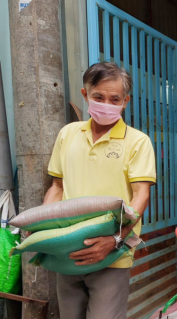 Nguyen Van Tuong, Uyen’s husband, carries two bags of rice to help the poverty-stricken local communities. Photo: Chi Cong / Tuoi Tre