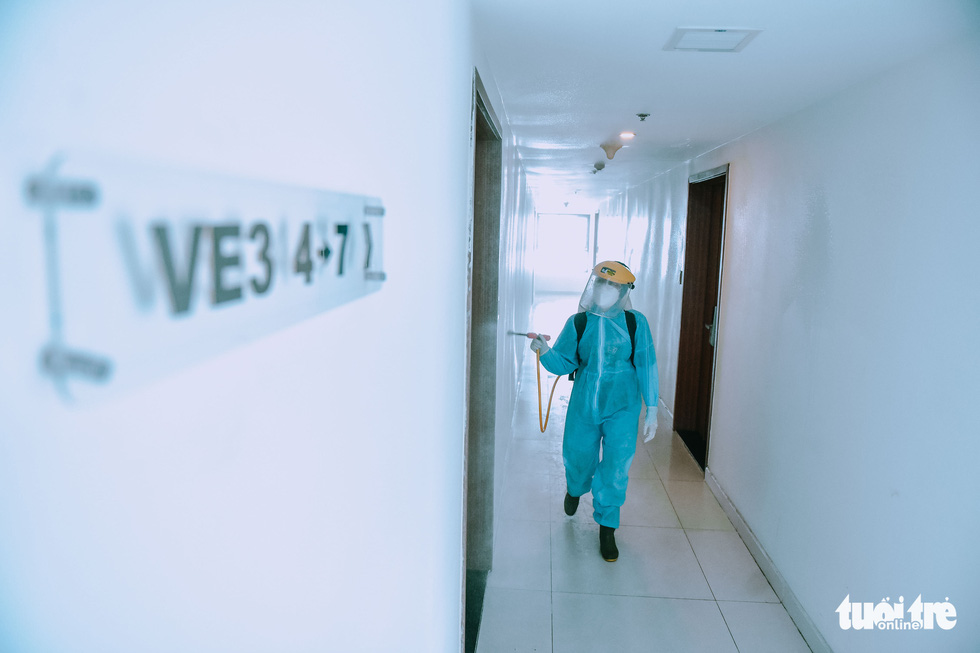 Luu Thi My Lil sprays disinfectant beside a 25-floor building based in Thu Duc City, Ho Chi Minh City. Photo: Ngoc Phuong / Tuoi Tre