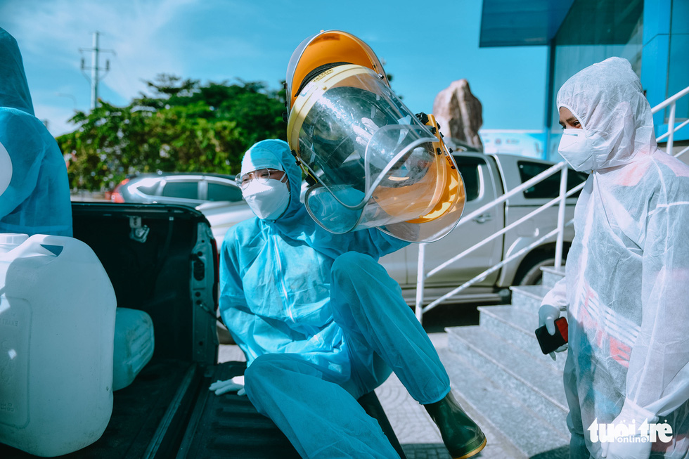 Young women jump onto a vehicle to start their day spraying disinfectant in high-risk COVI-19 areas in Ho Chi Minh City. Photo: Ngoc Phuong / Tuoi Tre