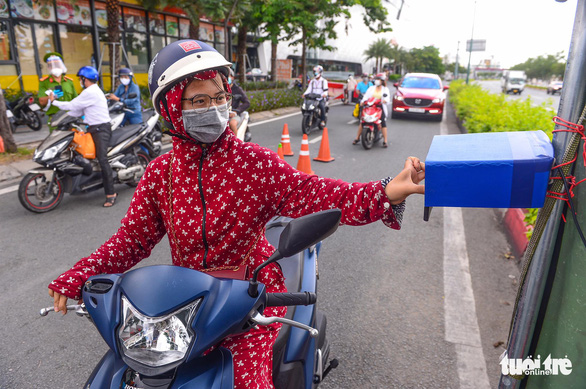 A woman is seen making movement declaration by holding up her QR Code on her phone to a scanner on Pham Van Dong Street, Ho Chi Minh City. Photo: Quang Dinh / Tuoi Tre