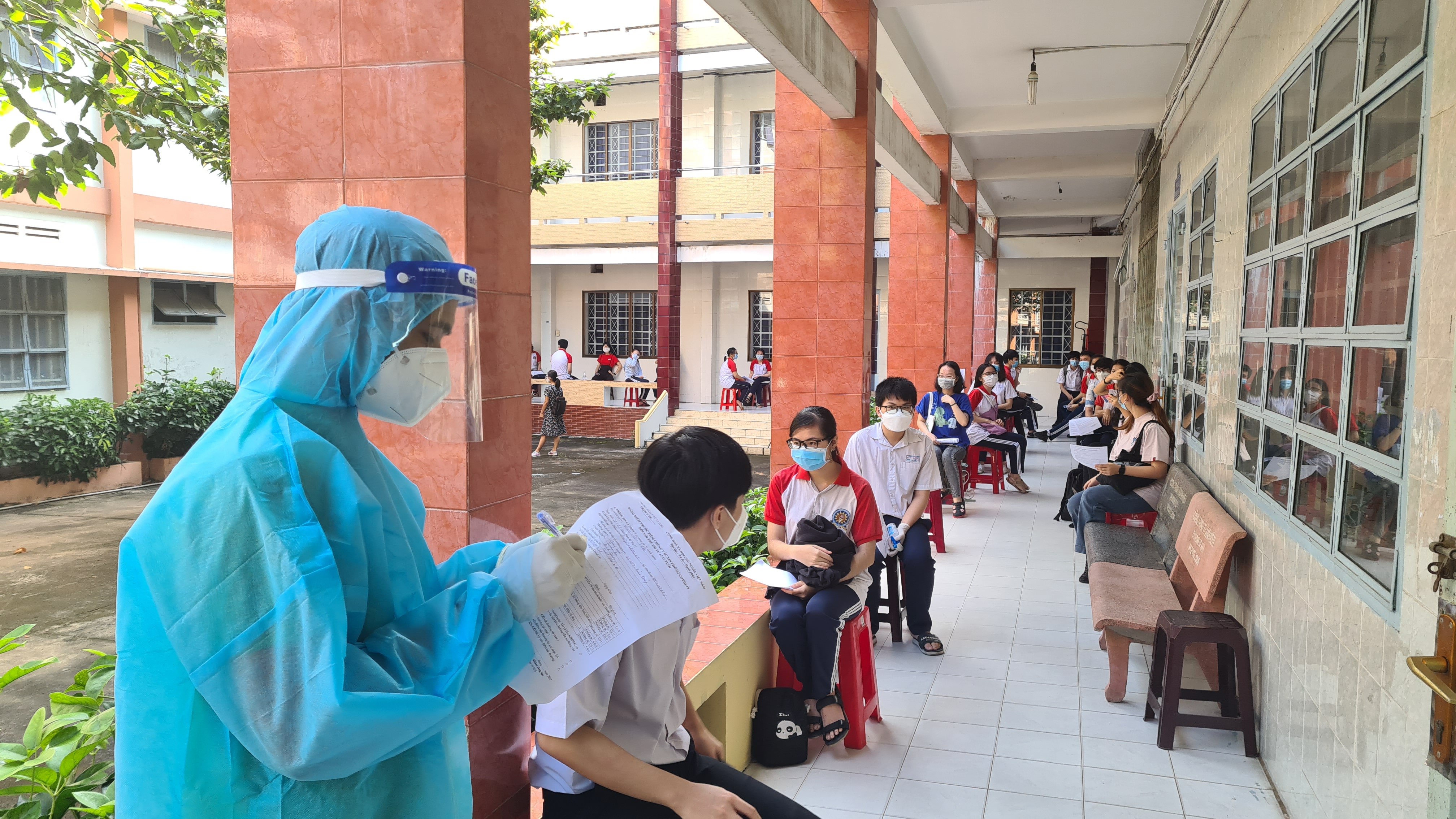 Students wait for their turn to receive COVID-19 vaccination at an inoculation site in Binh Duong Province, Vietnam, October 31, 2021. Photo: B.Son / Tuoi Tre
