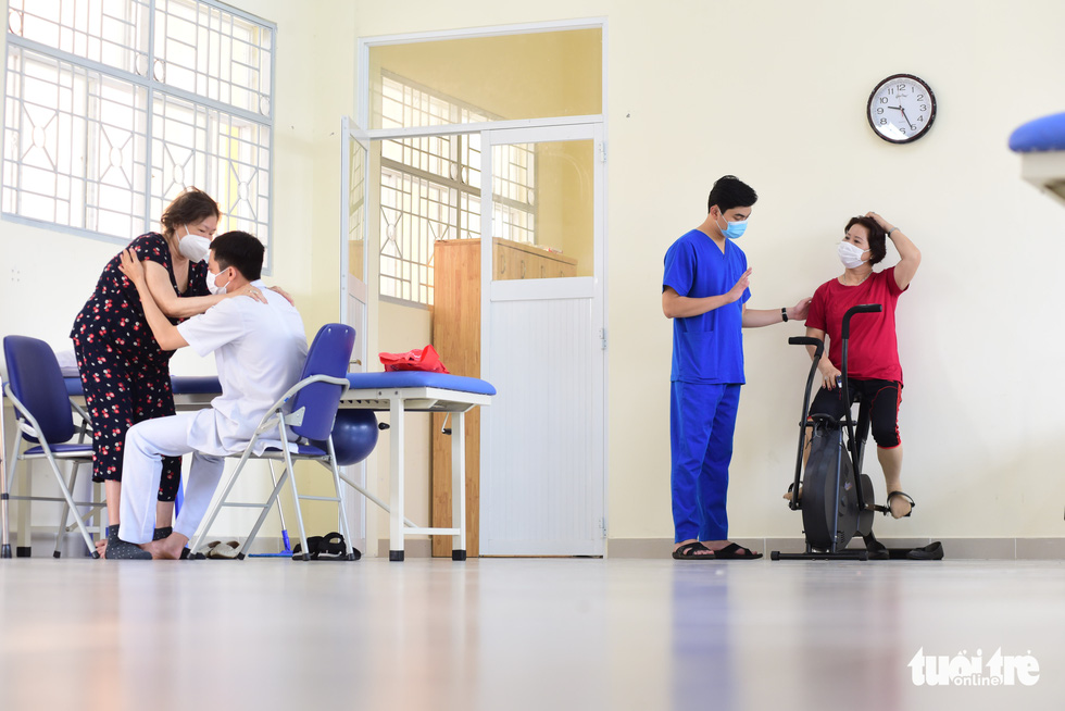 Some former COVID-19 patients are seen practicing physical movement exercises at the Le Van Thinh Hospital.