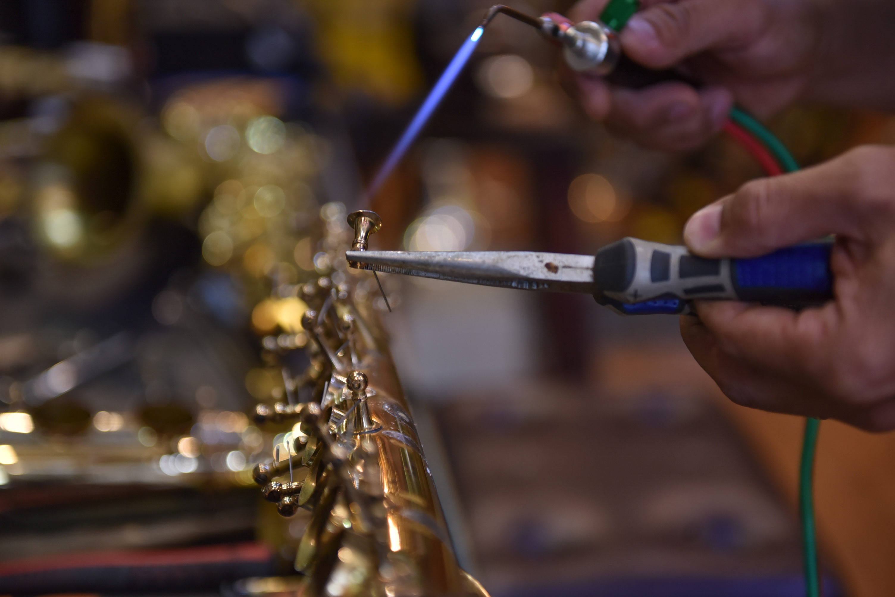 Nguyen Duy Khang uses a torch while separating the components of a saxophone at his repair shop in Tan Phu District in Ho Chi Minh City on December 6, 2021. Photo: Ngoc Phuong / Tuoi Tre News