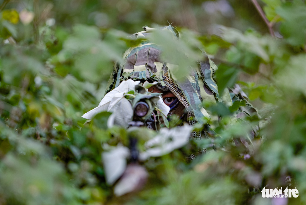 A camouflaged soldier takes aim at a target during training at the National Military Training Center 4 in My Duc District, Hanoi, Vietnam. Photo: Nam Tran / Tuoi Tre